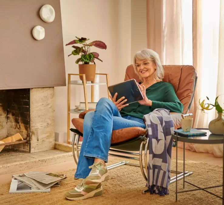 Vrouw van middelbare leeftijd speelt thuis een spelletje op haar tablet.